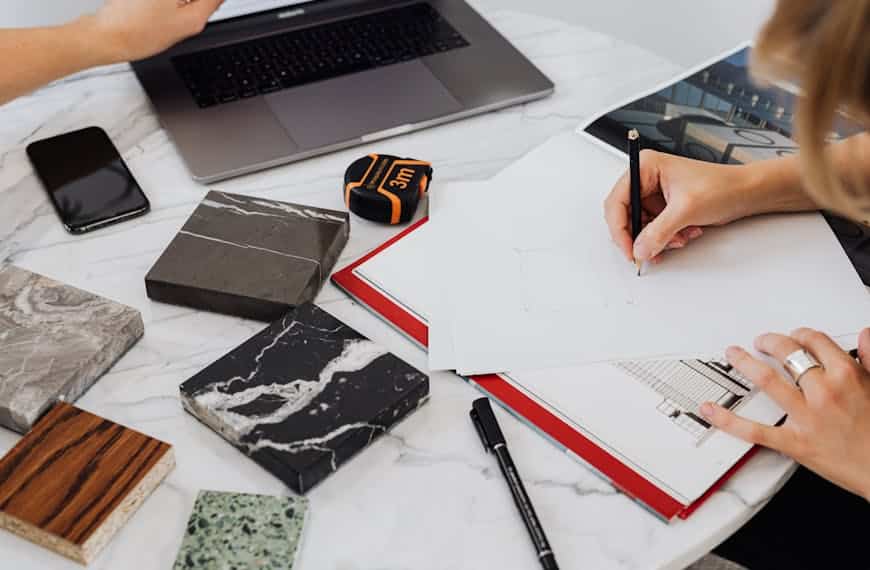 Workspace showing architectural design process with material samples and drawing.