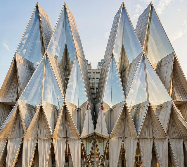Guadalajara Civic Sculpture combining crystalline glass and textile triangles in an origami-inspired design, reflecting the sky and surrounding buildings.