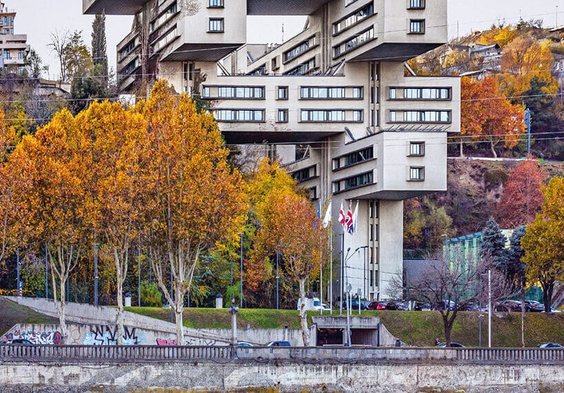 A multi-tiered Brutalist building along a riverbank in Tbilisi, Georgia, documented in Eastern Blocks