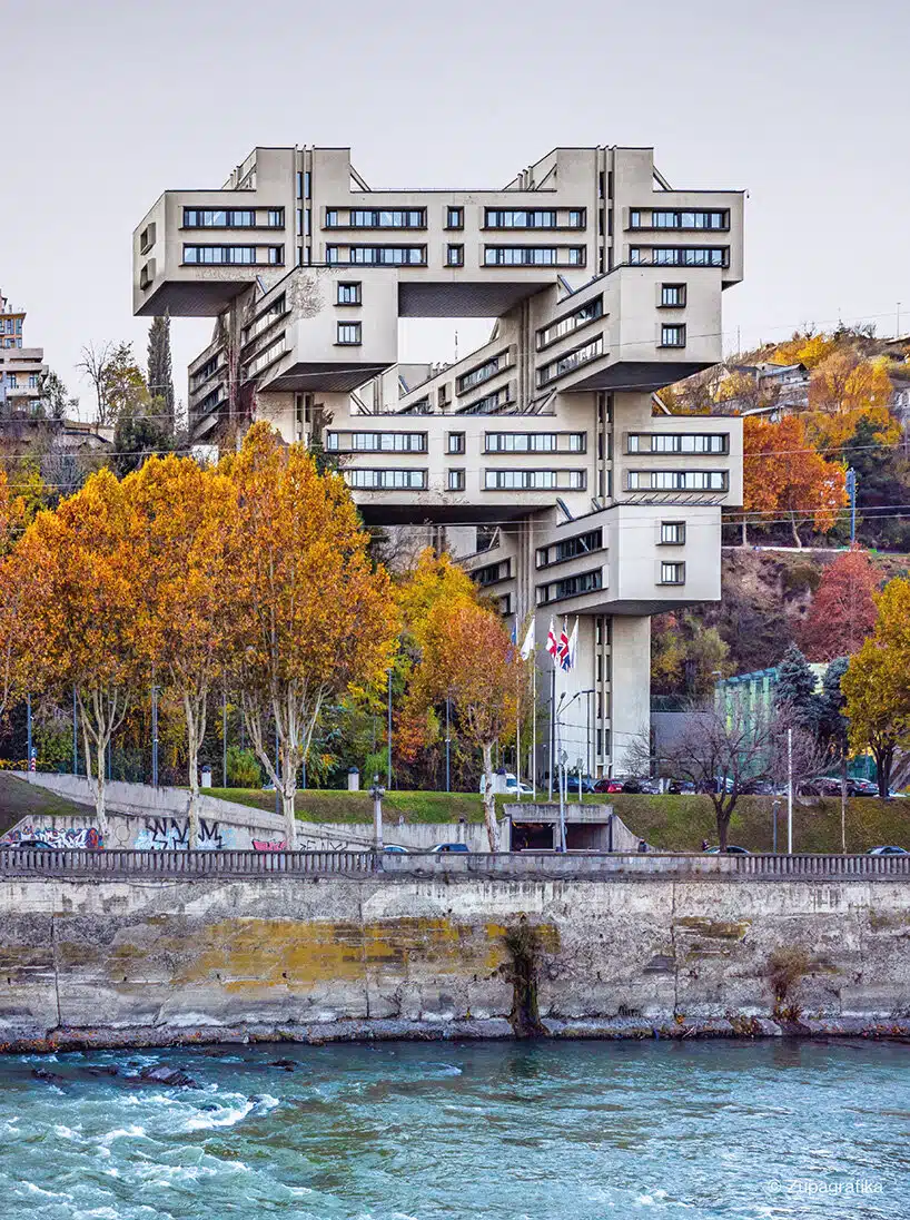 A multi-tiered Brutalist building along a riverbank in Tbilisi, Georgia, documented in Eastern Blocks