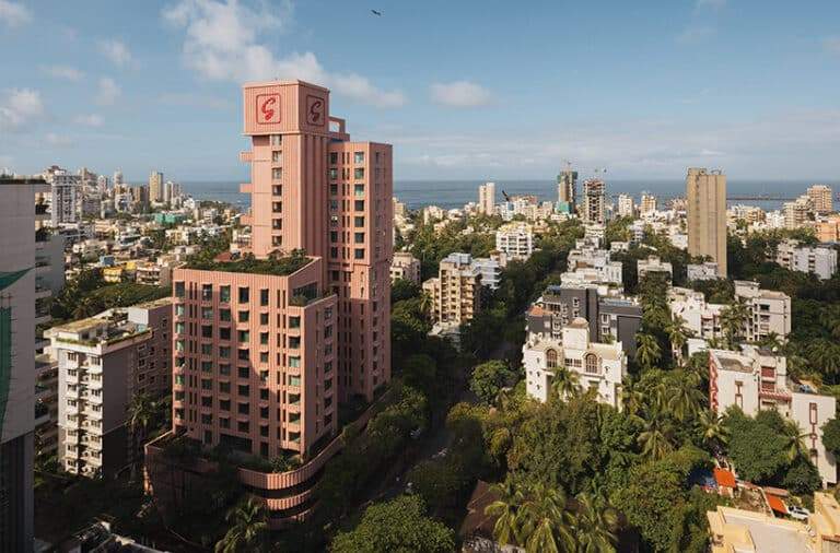 "A pink tiered tower stands out against Mumbai's skyline, overlooking the city and sea."
