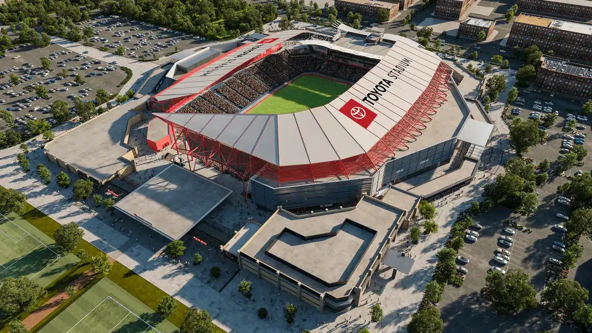 A large modern stadium with a red roof and seating surrounding a soccer field in the center
