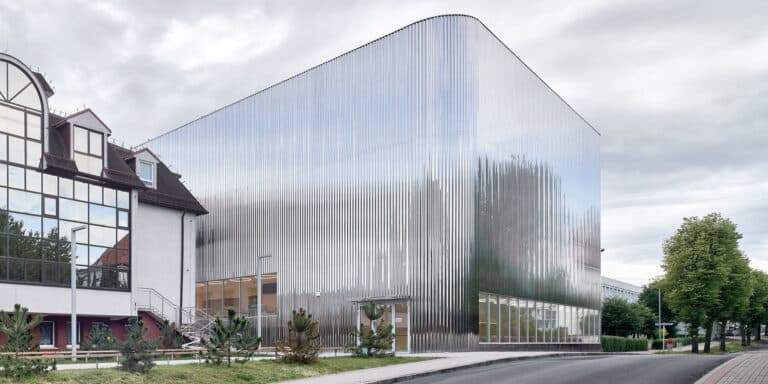 A modern building with a shiny metallic facade next to a traditional building.
