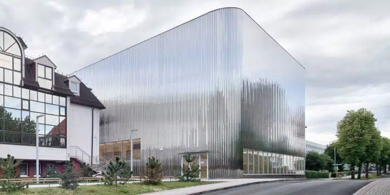 A modern building with a shiny metallic facade next to a traditional building.