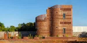 Side view of the House of Dancing Cactus in Pondicherry, India, showing layered, curved brick walls and cacti