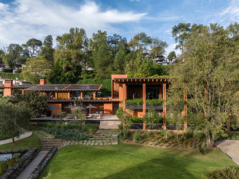 "Hotel Avándaro surrounded by lush greenery, showcasing its modern architectural design with solar panels and expansive green spaces."