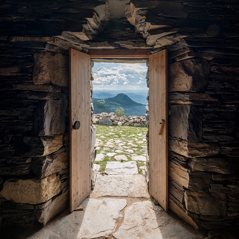 Mountain landscape view from inside a stone hut with an open door