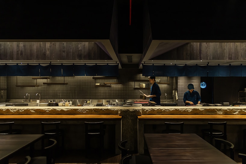 "صورة تُظهر المطبخ الداخلي لمطعم روكوشو، مع التركيز على استخدام الخرسانة والخشب في تصميمه المبتكر."