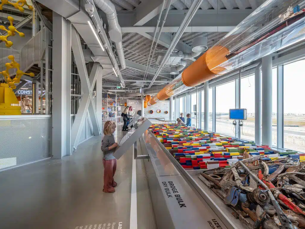 Child interacting with an educational exhibit about dry bulk cargo at the Portlantis Rotterdam exhibition.