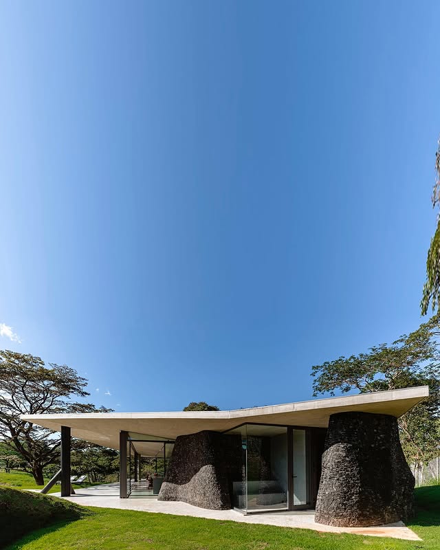 Front façade of the Seriema House with its organic design, floating roof, and natural stone elements.