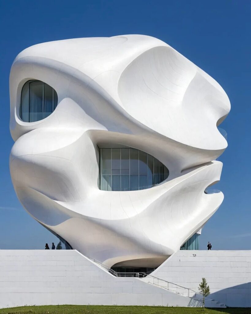 بنى معماري فريد بواجهة بيضاء منحنية تحتوي على فتحات دائرية، يعكس تصميمه استخدام الذكاء الاصطناعي في الهندسة المعمارية