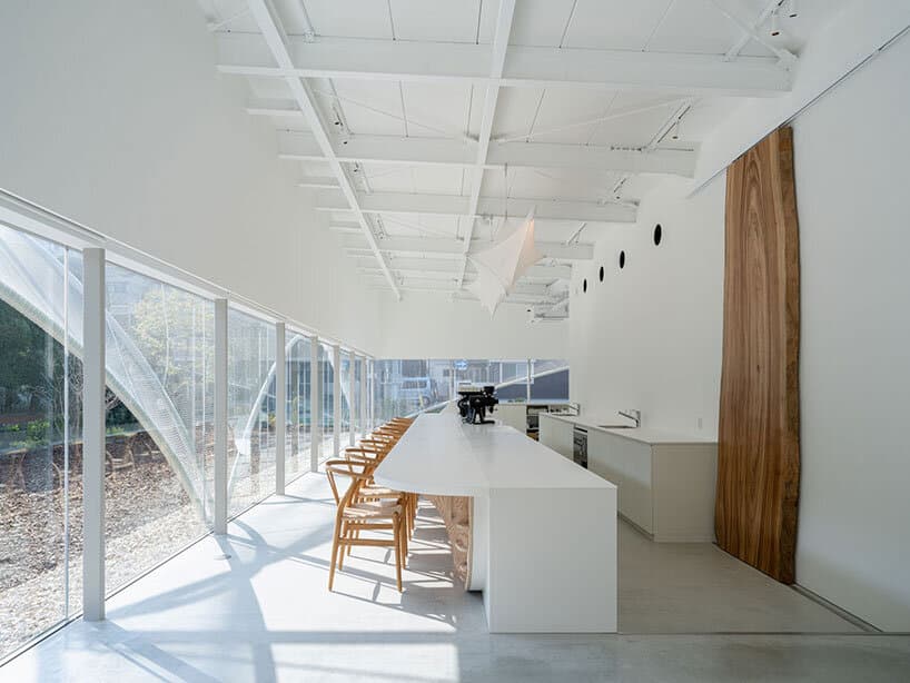 "Interior design of Cs Somme Café featuring a polished plaster counter and wooden tables overlooking the outdoor space."