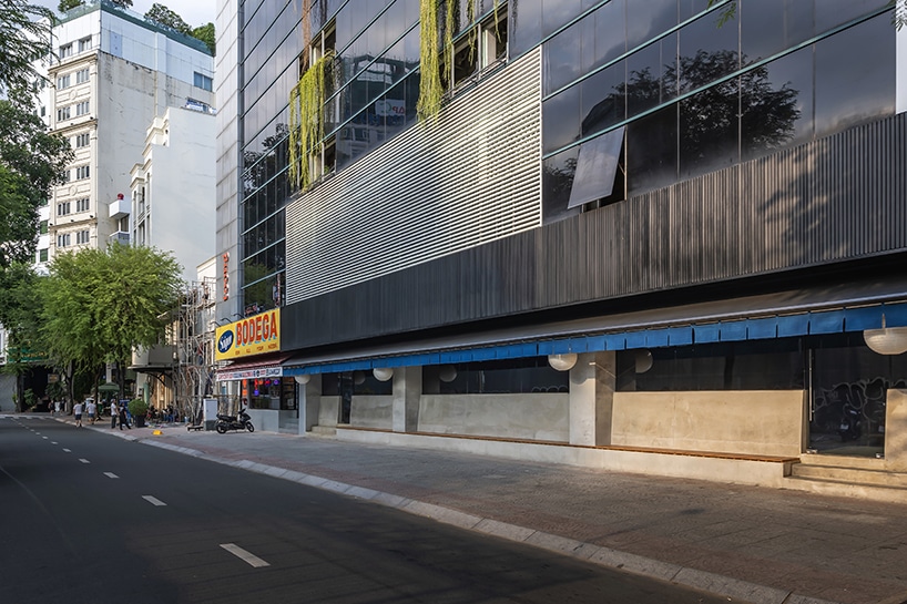 "صورة تُظهر الواجهة الخارجية لمطعم روكوشو في مدينة胡志明، مع استخدام الزجاج والخرسانة كعناصر رئيسية في تصميمه المبتكر."