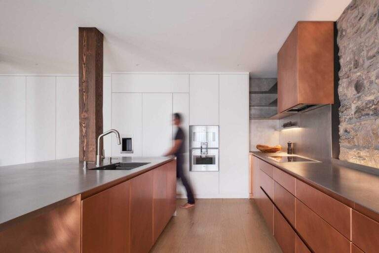 This modern kitchen in a renovated historic loft, features striking copper cabinetry and a stainless steel countertop.