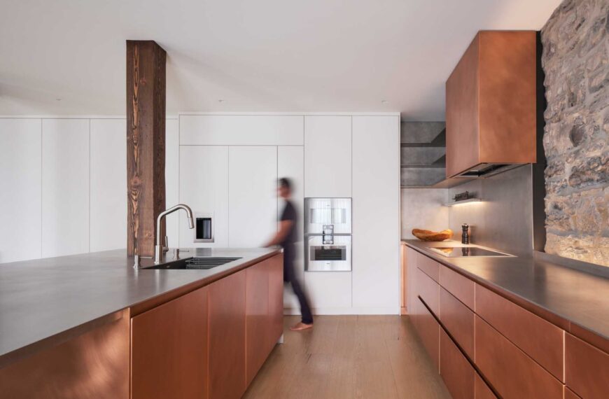 This modern kitchen in a renovated historic loft, features striking copper cabinetry and a stainless steel countertop.