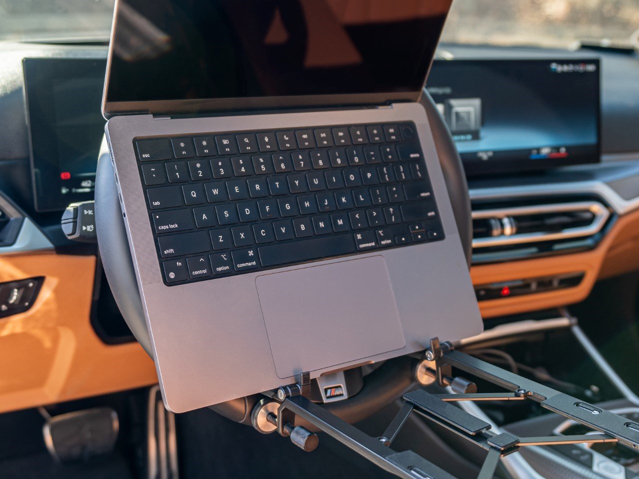 Man using a car table to work on laptop while parked