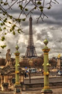 The iconic Eiffel Tower stands majestically in the heart of Paris, surrounded by ornate columns and lush green trees.