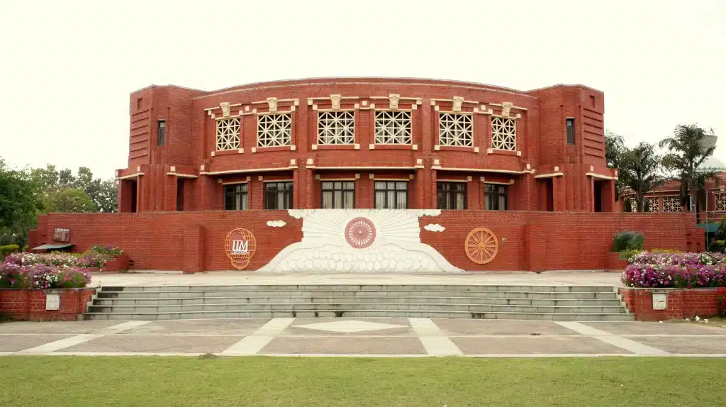 A red building with traditional architectural design featuring ornate glass windows, and a large mural in the front that includes geometric patterns and cultural symbols