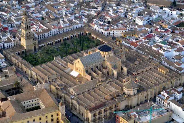"Aerial view of the Cordoba Mosque, showcasing its unique architectural design amid the white city."