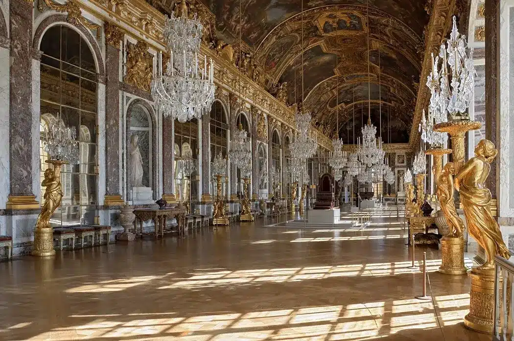 Grand Hall inside Versailles Palace showcasing ornate decorations and large windows