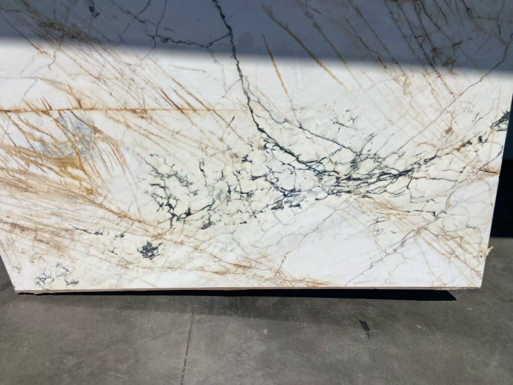 White marble slab with golden patterns and black veins during marble manufacturing