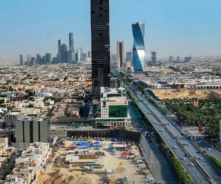 An aerial view of the Ajdan Towers under construction in Riyadh, featuring active construction equipment and site activity, with a backdrop of the city's modern skyline.
