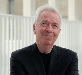 A man in a black suit smiling while