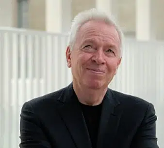A man in a black suit smiling while