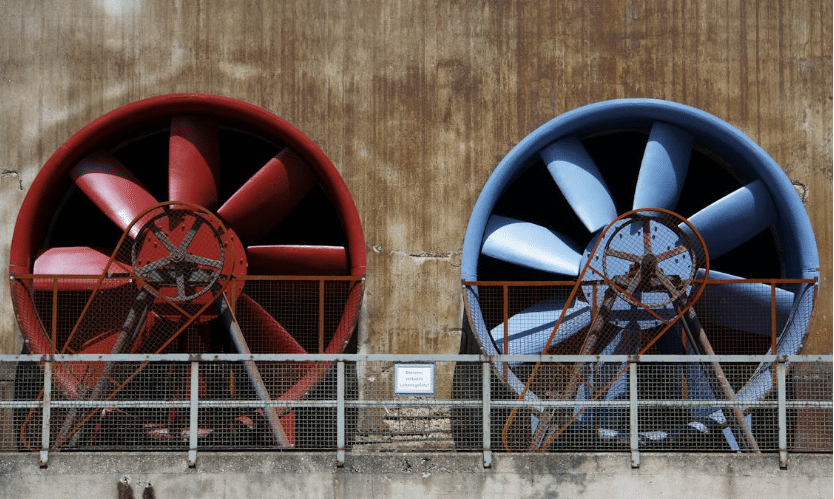 مروحتان صناعيتان كبيرتان، أحدهما حمراء والأخرى زرقاء، مثبتتان على جدار المبنى لضمان تهوية فعالة وتدفق الهواء.