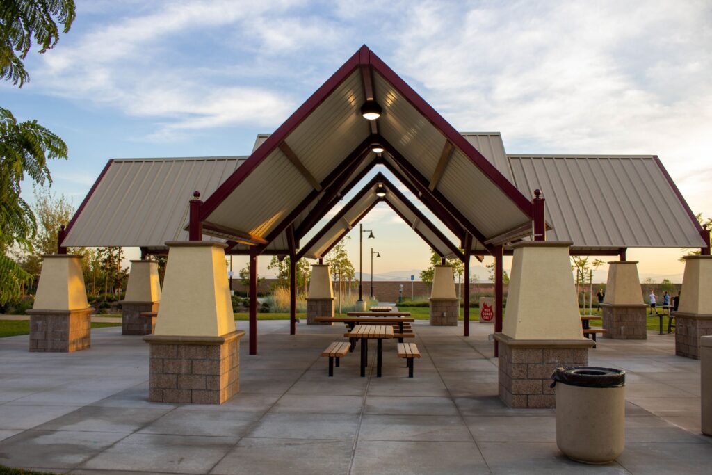 A public park area with sturdy wooden pavilions featuring tables and benches for outdoor dining or relaxation.