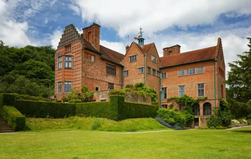 "English country house showcasing Tudor-style architecture with lush green gardens"