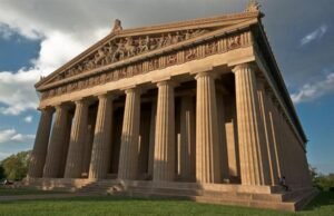 A grand classical temple with massive Doric columns and ornate pediments under a clear sky.