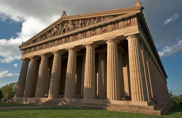 A grand classical temple with massive Doric columns and ornate pediments under a clear sky.