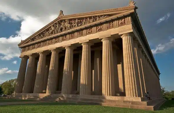 A grand classical temple with massive Doric columns and ornate pediments under a clear sky.