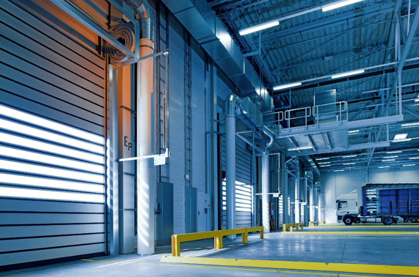 مصنع صناعي حديث يظهر تصميمًا داخليًا متطورًا مع أنظمة تهوية وضوء اصطناعية، بالإضافة إلى ممرات واضحة لحركة الشاحنات