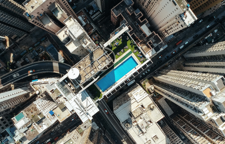 Aerial image of a dense urban area with tall, modern buildings and a rooftop pool, highlighting the integration of high-density development with sustainable design elements.