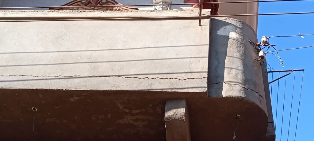 A concrete balcony showing significant cracks and deterioration due to weather exposure.