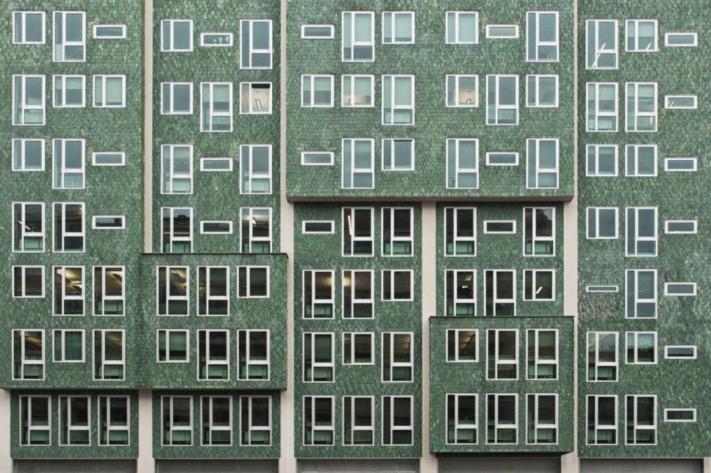 Modern building facade in Milan showcasing an innovative design with green tiles, reflecting smart urban design.