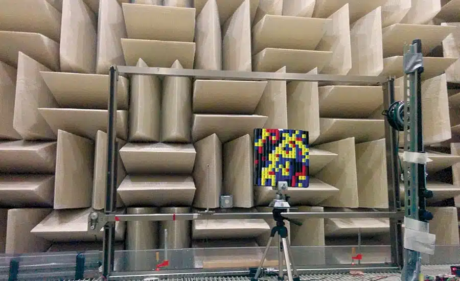 An anechoic chamber equipped with sound-absorbing panels, featuring a digital display showing a 3D model for acoustic analysis.