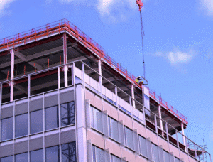 Workers installing curtain wall panels on the building structure during construction.