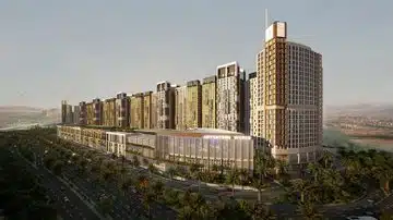 A photo of a modern city area with sleek, stylish buildings — some tall, some smaller — arranged neatly. The glass fronts catch the warm evening light, and there's a big road in front lined with greenery and walkways. The whole scene gives off a vibe of smart urban planning and contemporary design.