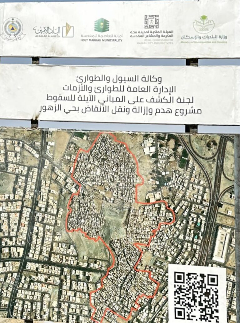 An aerial view of a densely populated urban area, with a highlighted red boundary outlining the Al-Zuhur neighborhood in Makkah. The image includes logos of various governmental and municipal entities involved in the urban redevelopment project. A QR code is visible in the bottom right corner, likely providing additional information about the clearance process.