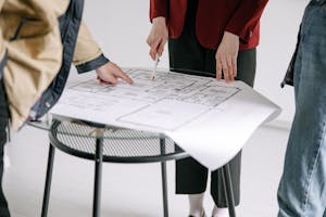 A group of people reviewing architectural blueprints on a table indoors.