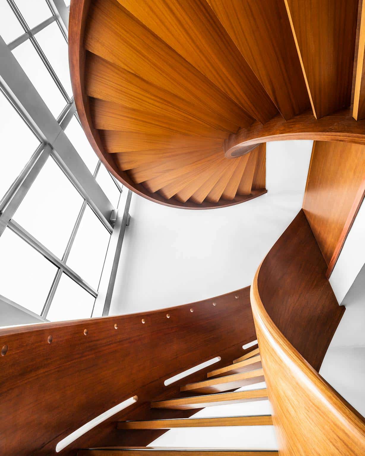 "سُلّم خشبي حلزوني بتصميم مستوحى من هندسة الأوريغامي، يبرز التطبيقات المعمارية للمواد خفيفة الوزن والقابلة للطي."