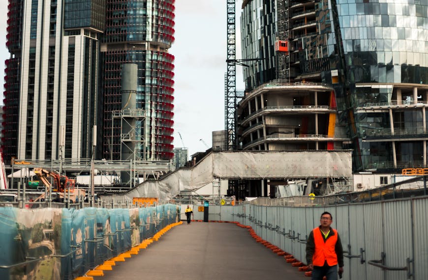 مشهد حضري حيوي يظهر ناطحات سحاب ومرافق نقل قيد الإنشاء مع رافعات تعمل بفعالية، يعكس تسارع تطوير البنية التحتية الحضرية والنقل بفضل تمويل إنشاءات النقل لعام 2025.