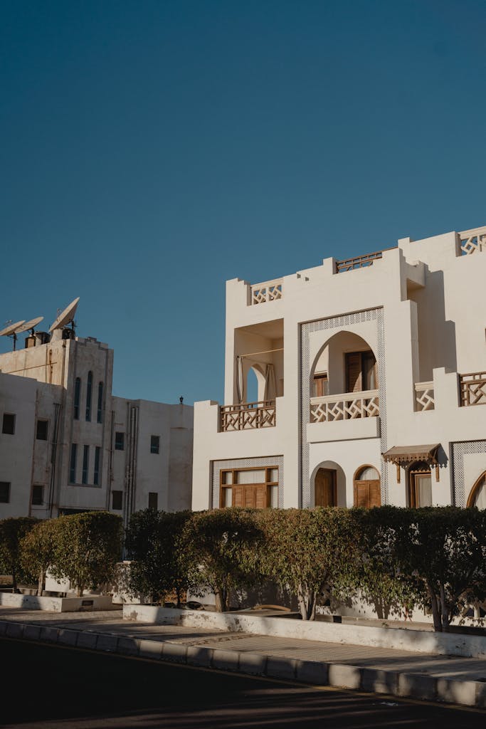 Exterior of a modern white building with clear sky and satellite dishes.