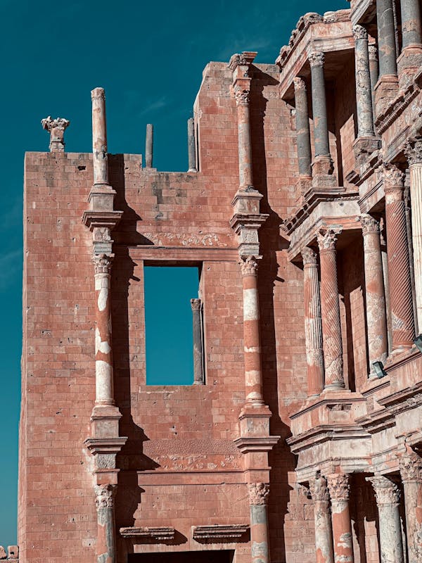 A composite column combining different materials, such as stone and wood, in an ancient building showcasing intricate carvings on columns and arches, with a clear blue sky in the background