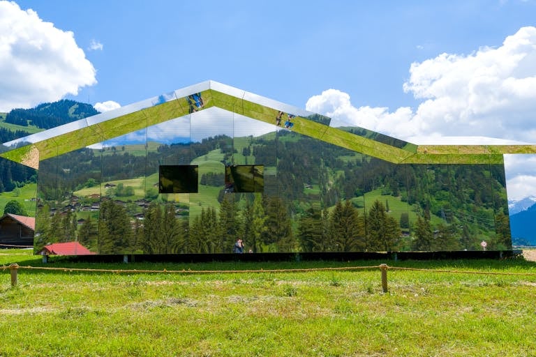 Mirror house reflecting scenic Swiss countryside in Saanen.