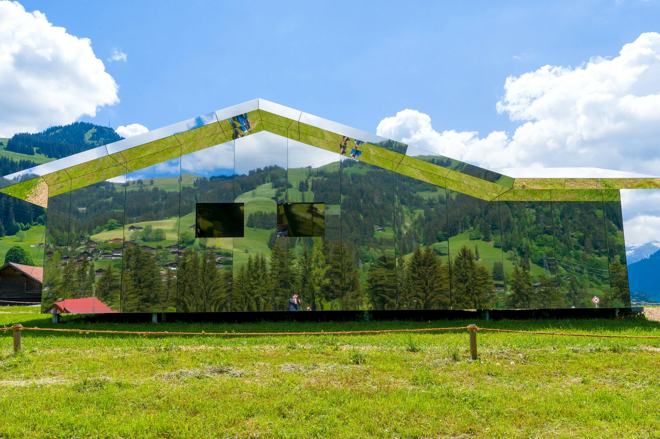Mirror house reflecting scenic Swiss countryside in Saanen.