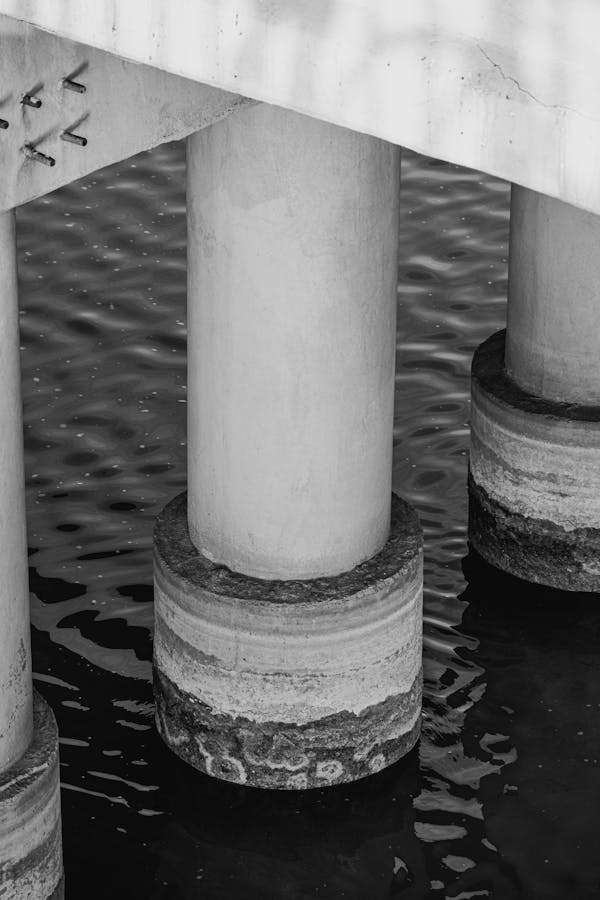 A concrete column showing the effects of water, with its lower part submerged in water.